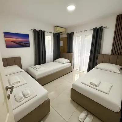 a room with three beds and a tv in it at Guest house, Small beach in Ulcinj