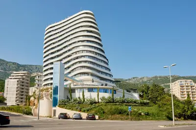 a large white building with cars parked in front of it at Skyline resort CG in Budva