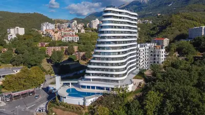 a tall white building with a pool in front of a city at Skyline resort CG in Budva