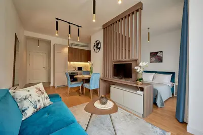 a living room with a blue couch and a bed at Skyline resort CG in Budva