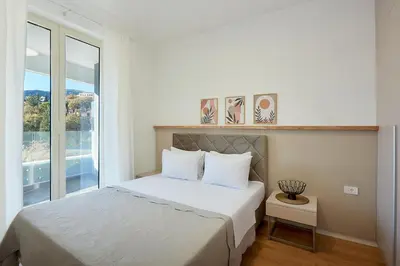 a bedroom with a white bed and a large window at Skyline resort CG in Budva