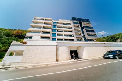 a woman standing in the doorway of a building with a car at Harmonia Sunrise Apartments in Budva