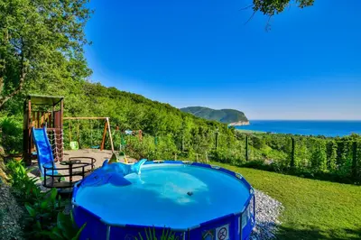 a blue pool in a yard next to the ocean at Pataki Guesthouse in Petrovac na Moru