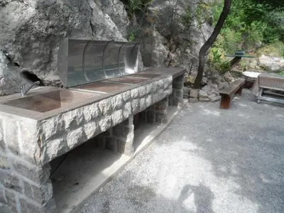 a stone bench with a sink in a park at Pataki Guesthouse in Petrovac na Moru