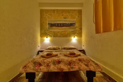a small bedroom with a bed with a painting on the wall at Pataki Guesthouse in Petrovac na Moru
