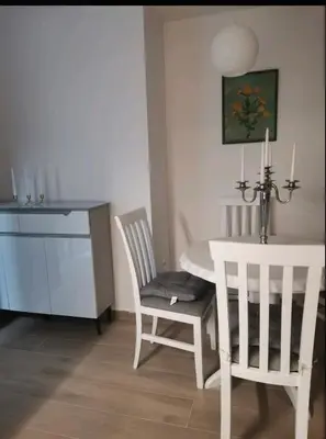 a dining room with a white table and two chairs and a table and a desk at Apartman Budva in Budva