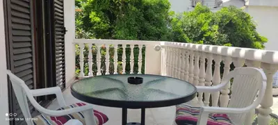 a glass table and two chairs on a balcony at House Irena in Budva