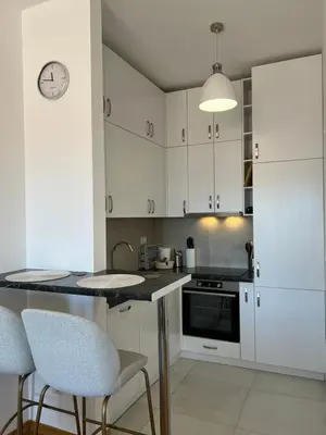 a kitchen with white cabinets and a table and chairs at Luxury Apartment SOHO CITY in Bar