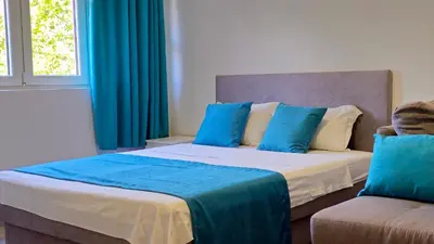 a bedroom with two beds with blue curtains and a couch at Zero Distance Studio in Podgorica