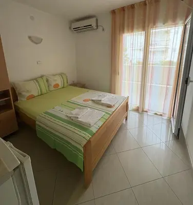 a bedroom with a bed with green sheets and a window at Apartmani Miladinović in Sutomore