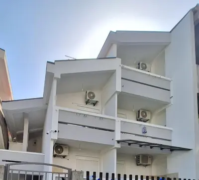 a white building with balconies on the side of it at Apartmani Miladinović in Sutomore