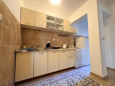 a kitchen with white cabinets and a washer and dryer at Apartman Sunce in Podgorica