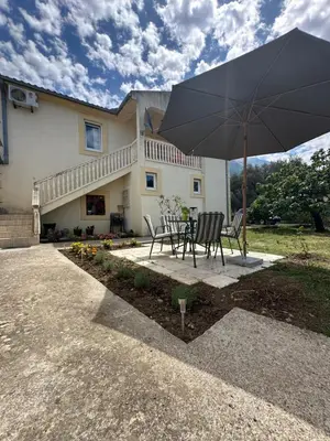 a table and chairs with an umbrella in front of a house at Stari Bar Apartments in Stari Bar