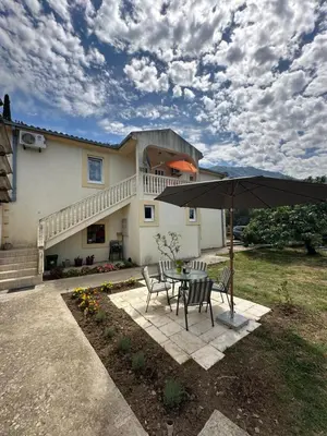 a table and chairs with an umbrella in front of a house at Stari Bar Apartments in Stari Bar