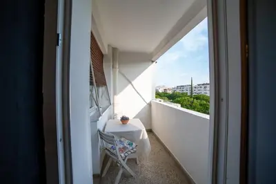 a white balcony with a table and a chair at Podgorica Boulevard Residence in Podgorica