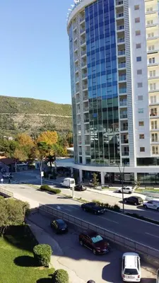 a parking lot with cars parked in front of a tall building at Budva Apartment in Budva