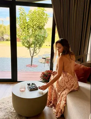 a young girl sitting on a couch next to a coffee table at LuxEcoCottage in Podgorica