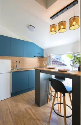 a kitchen with blue cabinets and a table with a stool at Little Heaven Escape in Budva