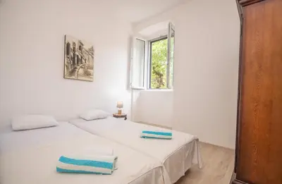 a white bedroom with two beds and a window at Central & quiet location inside Old town Kotor in Kotor