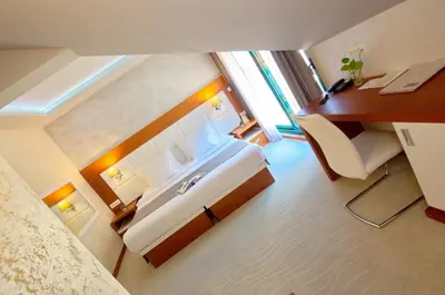 a room with a bed and a desk and a sink at Hotel Porto In in Kotor