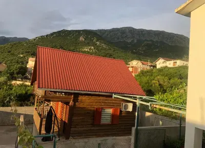 a house with a red roof with mountains in the background at Vikendica za odmor in Dobra Voda