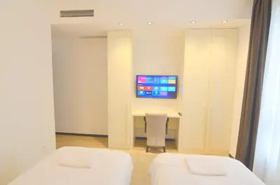 a room with two beds and a desk with a tv at Azure Corner Residence Budva - Seaside Living Apartments in Becici