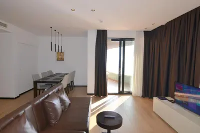 a living room with a couch and a dining room at Azure Corner Residence Budva - Seaside Living Apartments in Becici