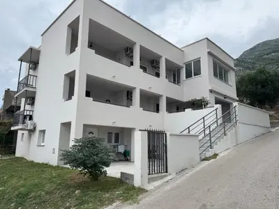 a white building with a gate on the side of a road at Apartmani in Sutomore