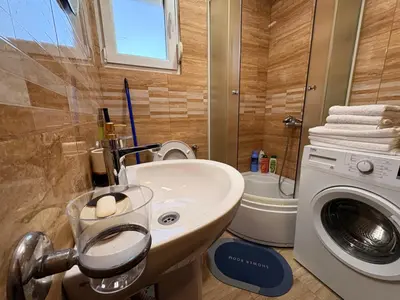 a bathroom with a sink and a washing machine at Gintas Comfort in Podgorica