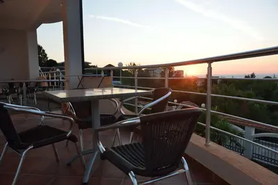 a balcony with a table and chairs and the sunset at Belvedere Apartments with Seaview in Dobra Voda