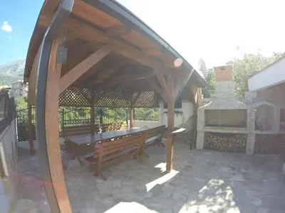 a wooden gazebo with two benches on a patio at Belvedere Apartments with Seaview in Dobra Voda