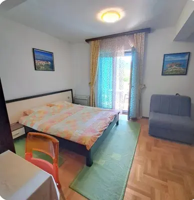 a bedroom with a bed and a chair and a window at Apartman Tijana in Budva