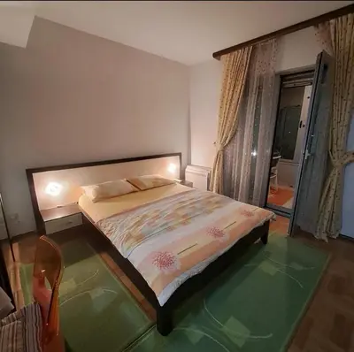 a bedroom with a bed and a chair and a window at Apartman Tijana in Budva