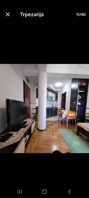 a living room with a flat screen tv and a kitchen at Apartman Tijana in Budva