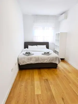 a bedroom with a bed and a wooden floor at Central Point Apartment in Podgorica