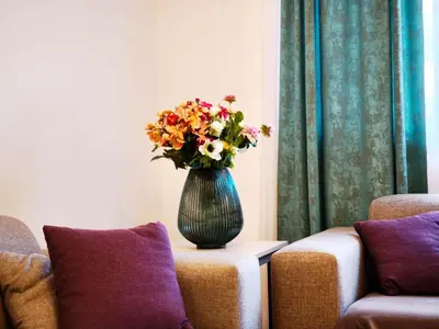 a vase with flowers sitting on a table in a living room at Central Point Apartment in Podgorica