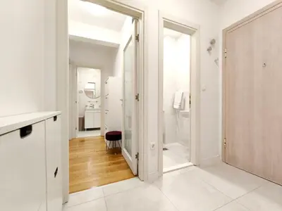 a white bathroom with a door leading to a bathroom with a toilet at Central Point Apartment in Podgorica