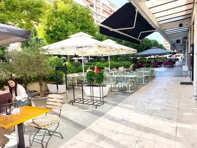 a patio with tables and chairs and umbrellas at Central Point Apartment in Podgorica