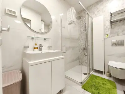 a white bathroom with a sink and a shower at Central Point Apartment in Podgorica