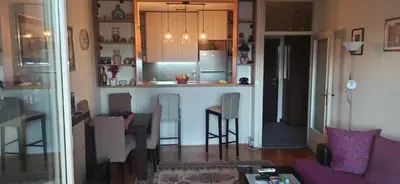 a kitchen and living room with a table and chairs at Cozy city center apartment in Podgorica