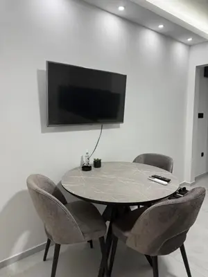 a table with chairs and a tv on a wall at Apartmani Zabjelo in Podgorica