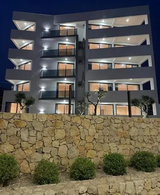 an apartment building at night with a stone wall at Seaview Komina apartments in Bar