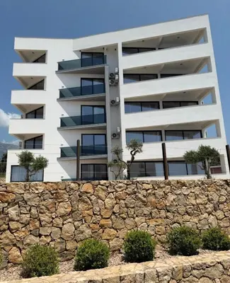 a white apartment building behind a stone wall at Seaview Komina apartments in Bar