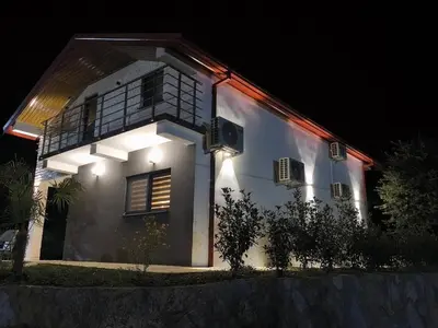 a white house with lights on it at night at Braća Velić in Bar