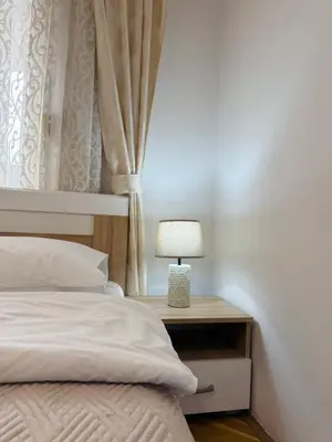 a bed with a lamp on a nightstand next to a window at Comfort corner Podgorica in Podgorica