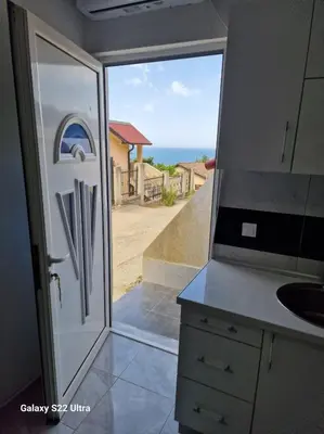 a kitchen with a door with a view of the ocean at Apartmani Kruče in Ulcinj
