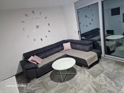 a living room with a couch and a clock on the wall at Apartmani Kruče in Ulcinj
