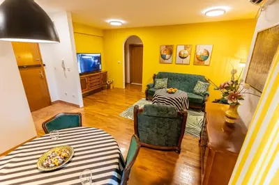 a living room with yellow walls and a table and chairs at Apartment Mia in Podgorica