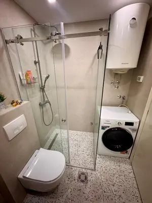 a bathroom with a shower and a washing machine at Bright & Modern Apartment in City Kvart in Podgorica