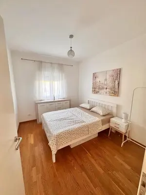 a white bedroom with a bed and a window at Bright & Modern Apartment in City Kvart in Podgorica